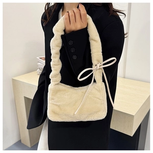 Detailed shot of cream plush handbag featuring ruffled handle and dainty ribbon bow