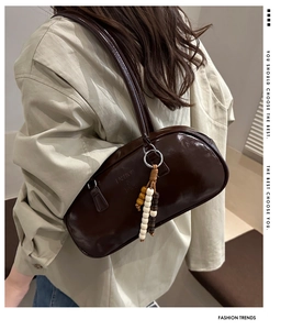 Detail of dark brown glossy shoulder bag with colorful wooden beads and fashion logo