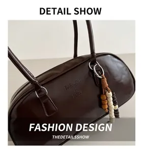 Detail of dark coffee Boston bag with engraved fashion text and wooden bead tassel
