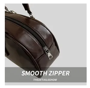 Close-up of smooth silver metal zipper on premium dark brown glossy leather baguette bag