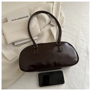 Detailed close-up of dark brown patent leather shoulder bag with fashion embossed texture