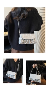 Detailed view of silver pleated cloud bag with metallic chain strap and fold-over flap