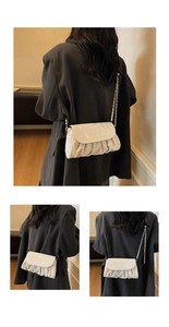 Detail of cream pleated cloud bag featuring silver chain strap and soft PU leather texture