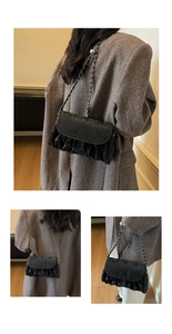 Macro detail of black pleated cloud bag showing soft leather texture and metal chain strap