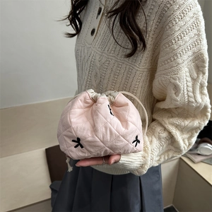 Quilted pink drawstring bucket bag with floral embroidery shown on a model's outfit
