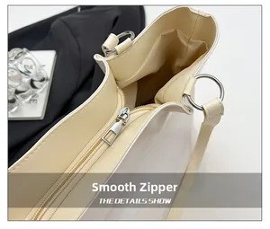 Close-up of smooth metal zipper and buckle on a cream leather tote bag with detail text