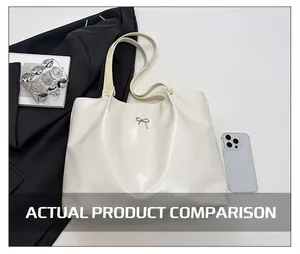 Detail view of large cream tote bag with silver metal bow and slim shoulder straps