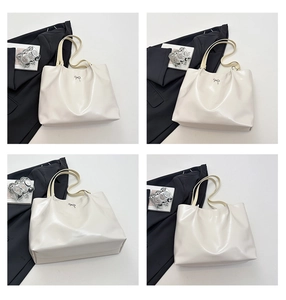 Detailed close-up of cream tote bag featuring a metallic bow and smooth faux leather finish