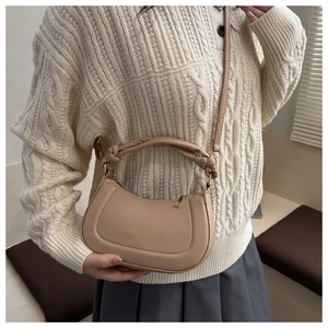 Detail of light brown crossbody bag featuring a thick woven twisted handle and gold logo