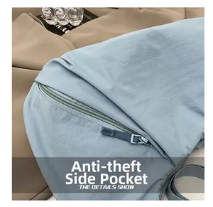 Detail view of the anti-theft side zipper pocket on a light blue nylon tote bag