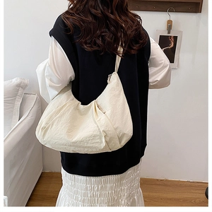 Close-up of cream crescent tote bag showing wrinkled fabric texture and draped design