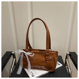Detailed view of caramel brown PU leather underarm bag with white lace bow decoration
