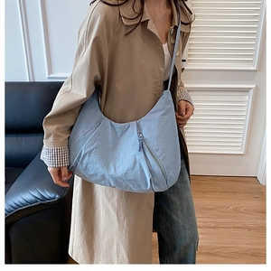 Detail of light blue crescent tote bag with pleated texture and zipper in daily scene