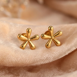 Macro shot of gold five-petal flower stud earrings with a polished mirror finish