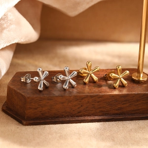 Detail of star-shaped floral stud earrings in polished gold and silver finishes