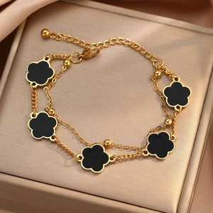 Zweilagiges goldenes Armband mit fünf schwarzen fünfblättrigen Blütenanhängern in einer Geschenkbox