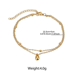 Close-up of double-layer gold beaded anklet featuring a polished teardrop charm and clasp