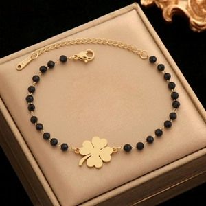 Bracelet trèfle doré avec perles noires et fermoir mousqueton réglable sur boîte