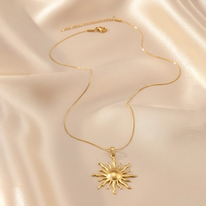 Detail of matte gold sun pendant necklace on champagne silk showing the clasp and chain