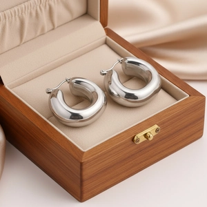 Polished chunky silver U-shaped hoop earrings displayed in a luxury wooden jewelry box