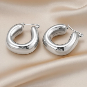 Detailed view of U-shaped silver stainless steel hoop earrings on champagne satin