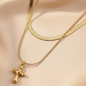 Vue détaillée du collier double rang doré avec chaîne serpent et pendentif en croix