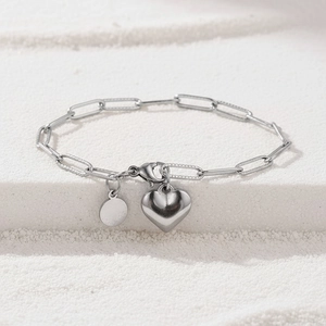 Détail du bracelet trombone en acier inoxydable argenté avec breloques cœur et rondes