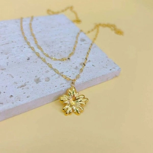 Macro shot of gold floral pendant necklace with 3D petals on a white stone display