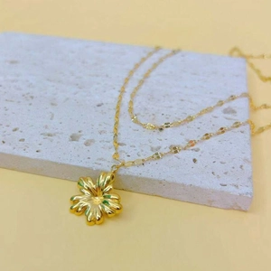 Detailed macro view of a golden flower pendant with 3D metallic petal texture on a fine chain
