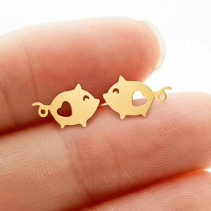 Minimalist gold hollow pig earrings with heart detail shown on finger for scale