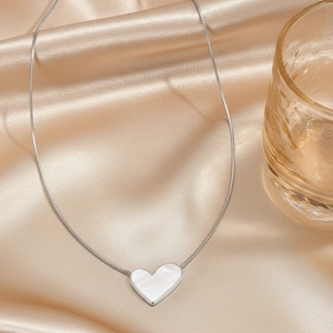 Elegante collana in acciaio inossidabile con cuore in madreperla su sfondo di seta