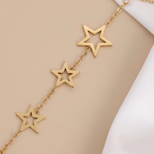 Detail of gold finger bracelet featuring hollow star charms on elegant silk fabric