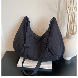 Detail of black crescent crossbody bag in lightweight nylon with adjustable strap and buckle