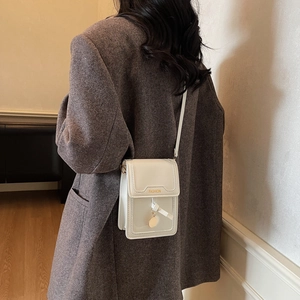 Minimalist white square crossbody phone bag with FASHION logo worn over a grey blazer
