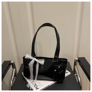 Detail of black glossy Boston bag with white lace bow and silver stud embellishments