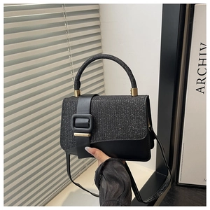 Detail of black crossbody bag with sequin flap and large square gold buckle closure