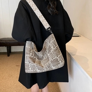 Modern woven geometric shoulder bag with ethnic patterned strap worn by a model