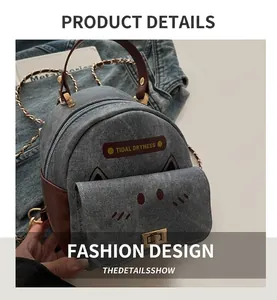 Detail of denim cat-shaped backpack with brown leather trim and golden square buckle