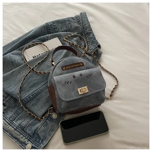 Detail of cat embroidery and vintage metal lock on mini patchwork backpack with chain strap