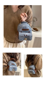 Detailed view of cat-shaped denim backpack with leather trim and gold chain accents