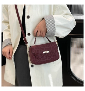 Detail of dark red leopard print handbag with metallic gold lock and textured finish
