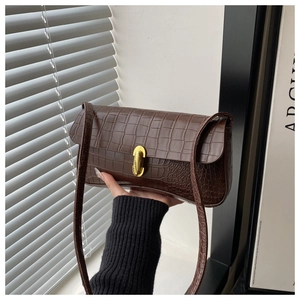 Detail of dark brown croc-effect shoulder bag with a gold rectangular metal clasp