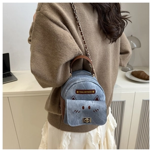 Detail of blue denim mini backpack featuring cat design and gold swivel lock closure