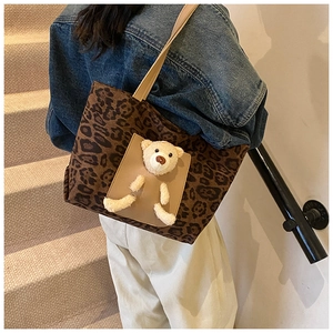 Detailed close-up of leopard print canvas tote bag featuring a cute plush bear detail