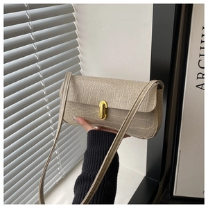 Close-up of the elegant crocodile-patterned beige leather bag with a gold metal clasp