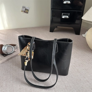 Large black tote bag with white contrast stitching and silk scarf on the handle