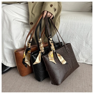 Close-up of vintage tote bags in brown and black with decorative silk scarves handles