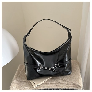 Detail of glossy black leather hobo bag with silver buckles and punk style straps
