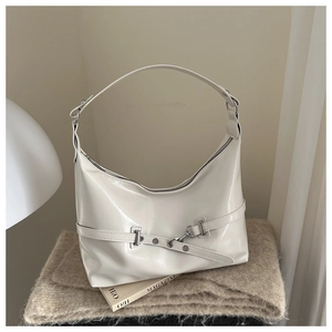 Detail of minimalist beige leather shoulder bag with silver hardware on a cozy background