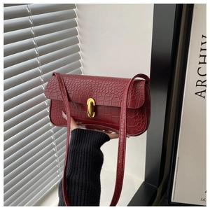 Close-up of dark red crocodile embossed leather texture with golden metal twist lock
